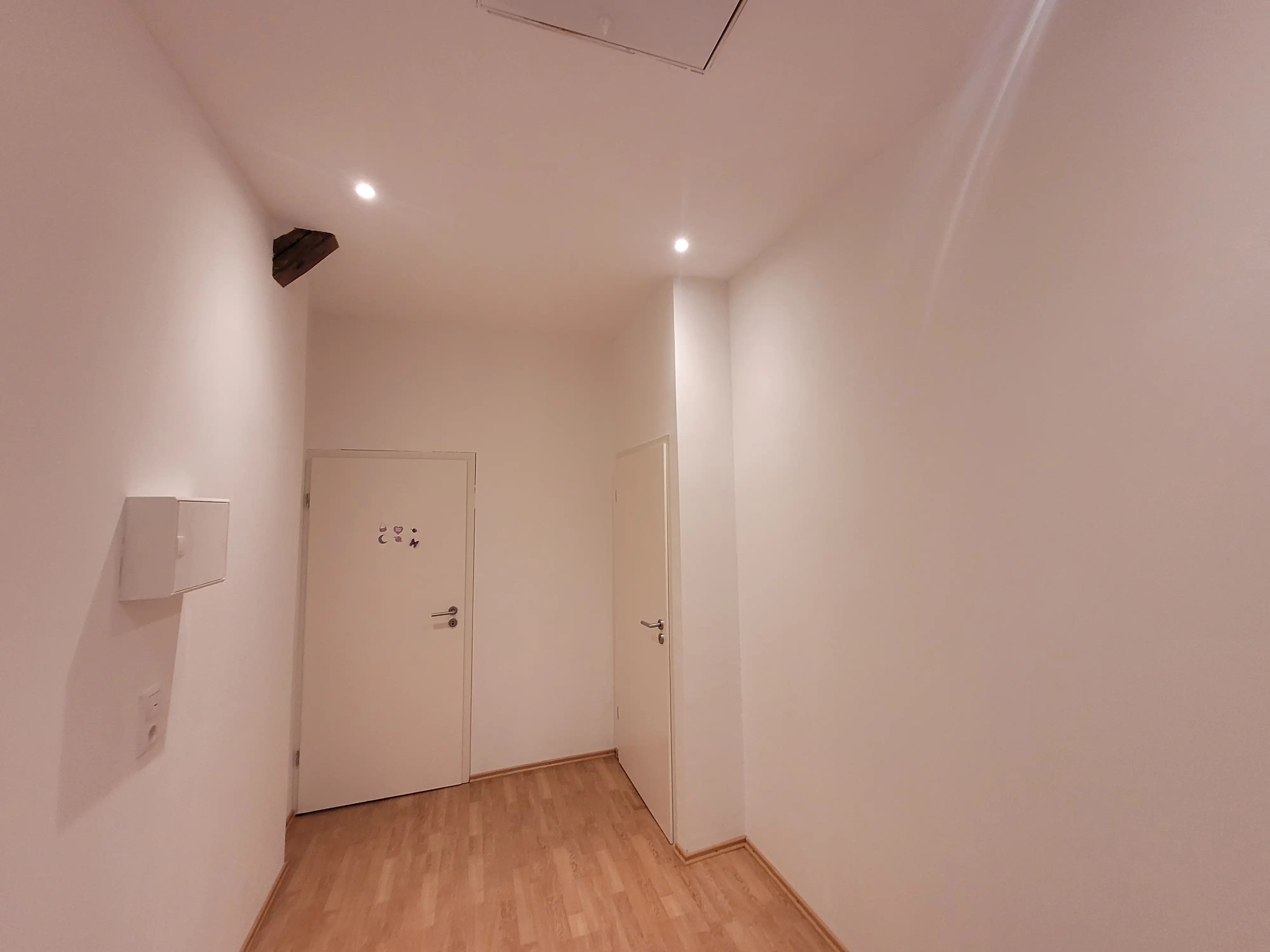 Weiß gestrichener Flur mit kleinen Smart-LEDs und neu verlegtem Laminat.