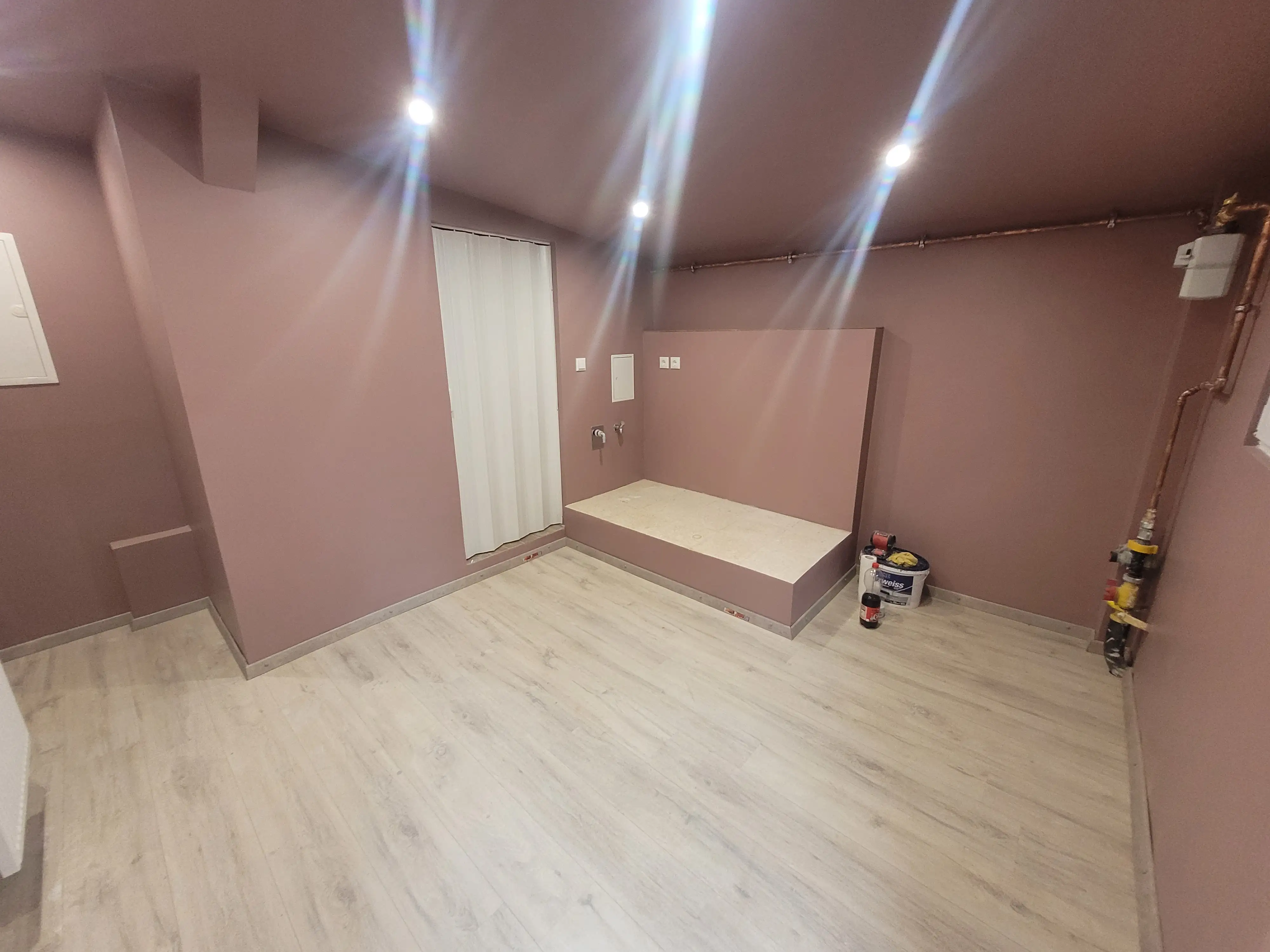 (3/3) Frisch gestrichene Wand mit abwaschbarer Dispersionsfarbe und Smart-LEDs, dazu neu verlegter Laminatboden.