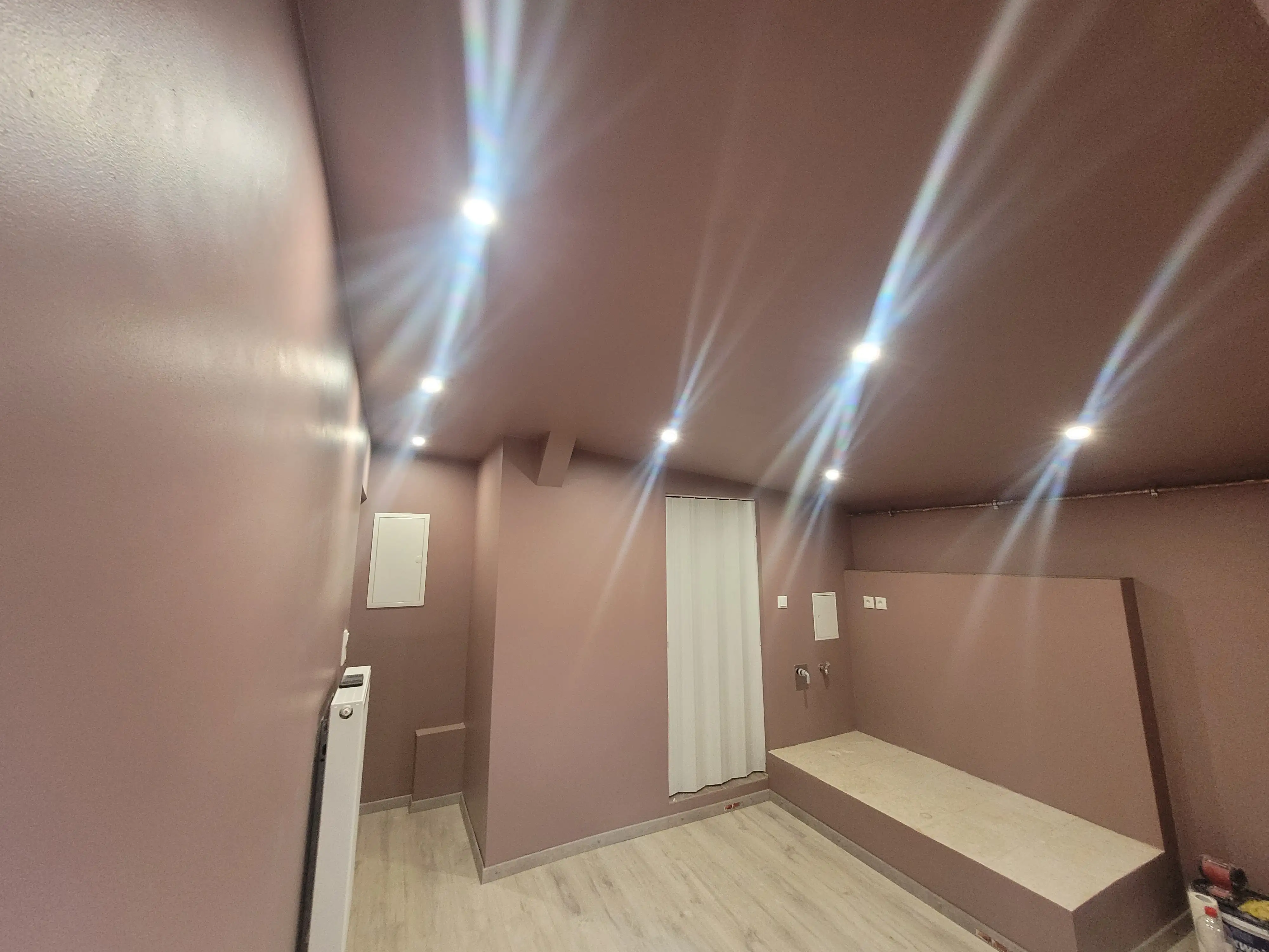 Frisch gestrichene Wand mit abwaschbarer Dispersionsfarbe und Smart-LEDs, dazu neu verlegter Laminatboden.